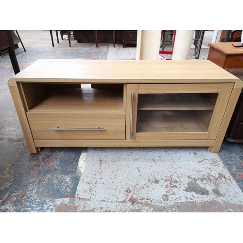 31 - A modern oak effect TV stand with one drawer and one glazed door - approx. 54cm high x 130 wide x 41... 