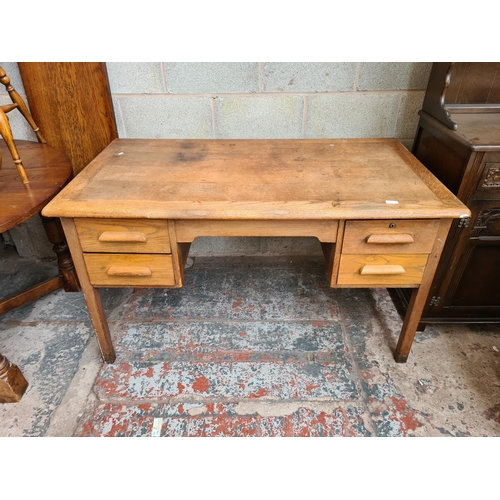 116 - A mid 20th century oak office desk with four drawers - approx. 76cm high x 135cm wide x 76cm deep