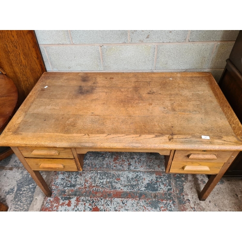 116 - A mid 20th century oak office desk with four drawers - approx. 76cm high x 135cm wide x 76cm deep