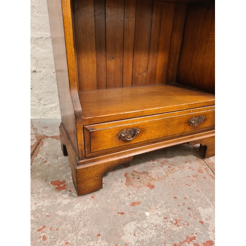 26 - A mid/late 20th century solid oak four tier waterfall bookcase with lower drawer - approx. 128cm hig... 