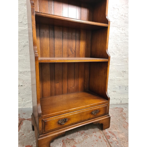 26 - A mid/late 20th century solid oak four tier waterfall bookcase with lower drawer - approx. 128cm hig... 