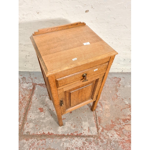 64 - An early 20th century oak bedside cabinet with one drawer and one cupboard door - approx. 82cm high ... 