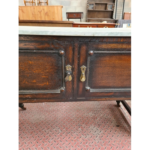 88 - An early 20th century oak and marble top two door wash stand - approx. 75cm high x 108cm wide x 48cm... 