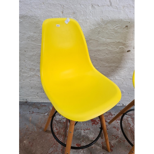 93 - A pair of modern Eames style yellow plastic and beech kitchen barstools - approx. 109cm high
