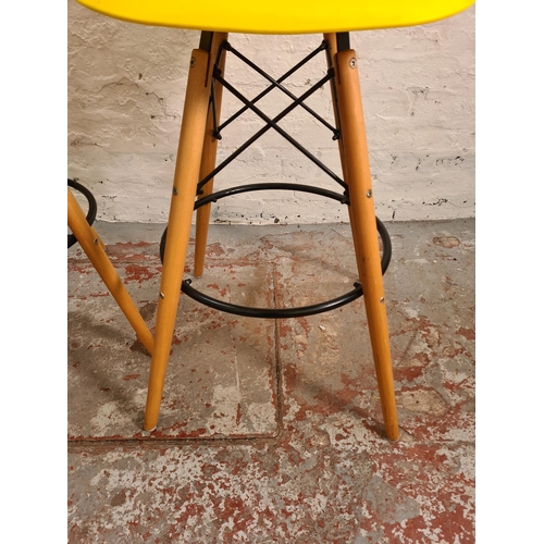 93 - A pair of modern Eames style yellow plastic and beech kitchen barstools - approx. 109cm high