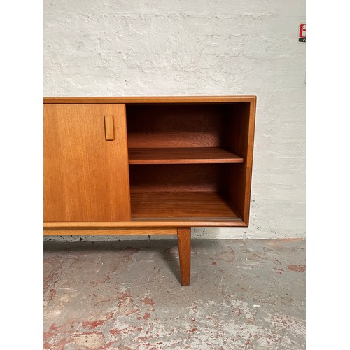 104 - A mid 20th century teak sideboard with four sliding doors, four internal drawers and shelving - appr... 