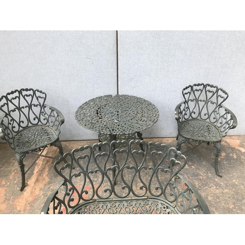 676 - A green painted cast aluminium four piece patio set comprising two seater bench, two armchairs and o... 