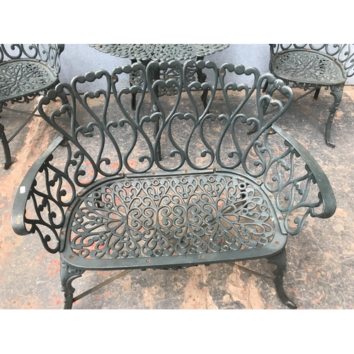 676 - A green painted cast aluminium four piece patio set comprising two seater bench, two armchairs and o... 