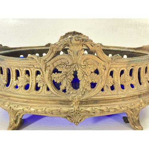 194 - A 19th century style gilt metal twin handled bowl with blue glass liner - approx. 15cm high x 41cm w... 