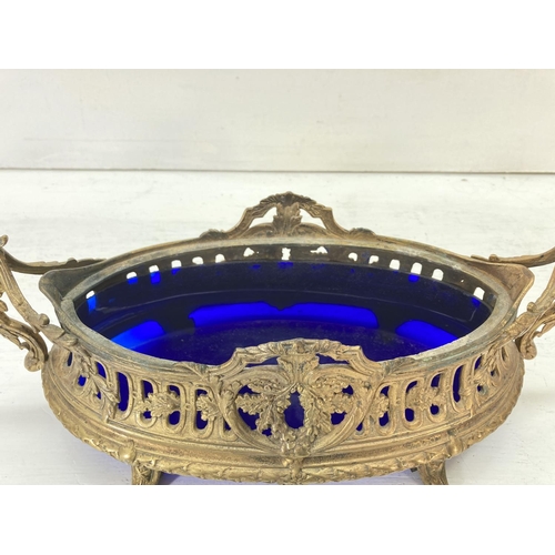 194 - A 19th century style gilt metal twin handled bowl with blue glass liner - approx. 15cm high x 41cm w... 