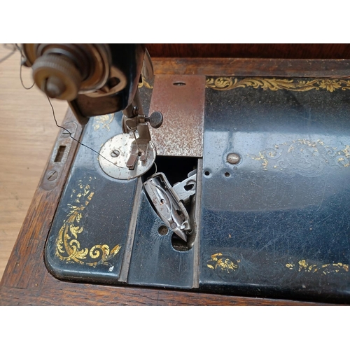 613 - A cased antique Singer hand crank sewing machine (Serial No: F8123225) with attachments