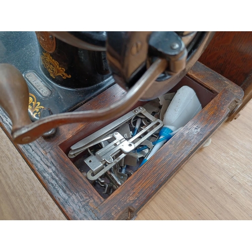 613 - A cased antique Singer hand crank sewing machine (Serial No: F8123225) with attachments