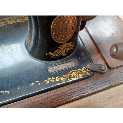 613 - A cased antique Singer hand crank sewing machine (Serial No: F8123225) with attachments