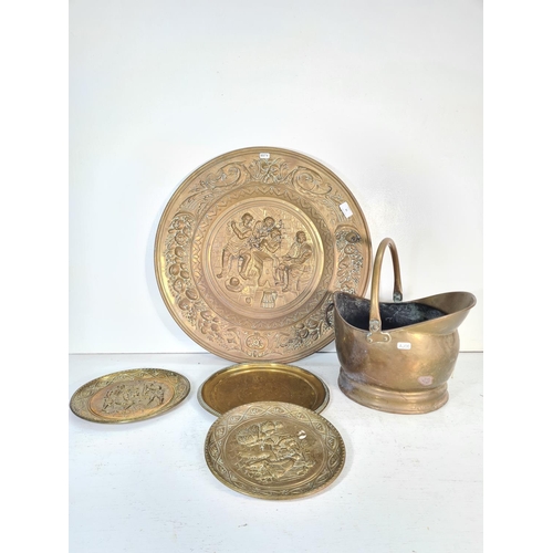 58 - Five pieces of brassware, one Victorian helmet coal scuttle and four various chargers - largest appr... 