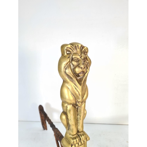 63 - A pair of brass lion design fire dogs - approx. 44cm high x 24cm wide x 42cm deep