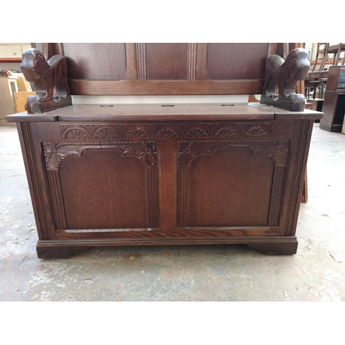 253 - A mid 20th century oak monks bench with lion design armrests and hinged lid - approx. 98cm high x 95... 