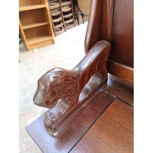 253 - A mid 20th century oak monks bench with lion design armrests and hinged lid - approx. 98cm high x 95... 