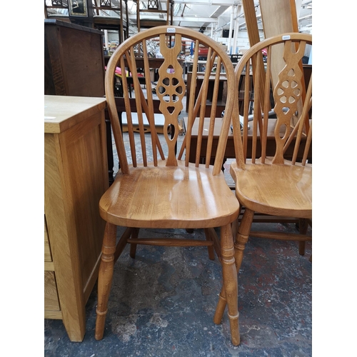 255 - A set of four modern solid beech wheel back dining chairs