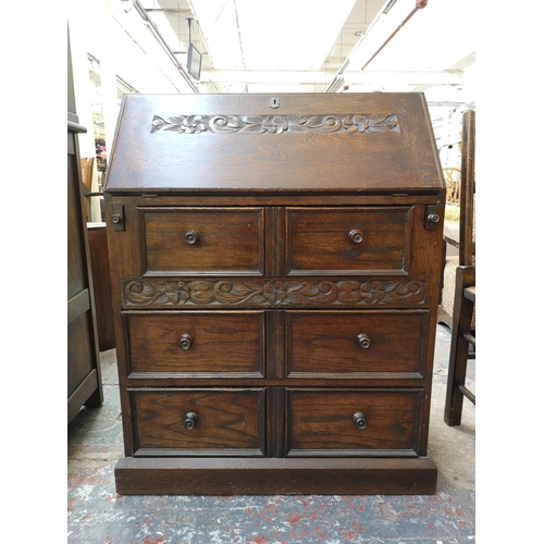 268 - A mid/late 20th century oak bureau with carved floral design, three drawers and fall front - approx.... 