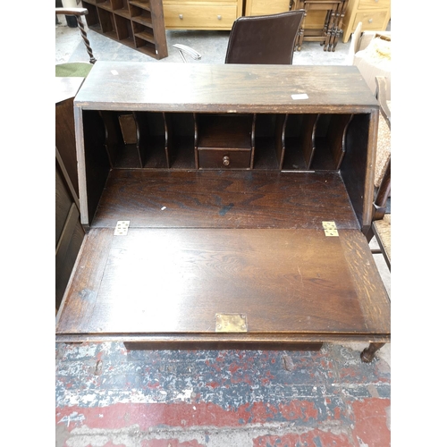 268 - A mid/late 20th century oak bureau with carved floral design, three drawers and fall front - approx.... 