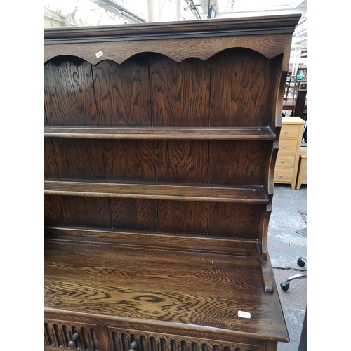 269 - A late 20th century oak linenfold Welsh dresser with upper two tier plate rack, two drawers and two ... 