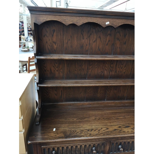 269 - A late 20th century oak linenfold Welsh dresser with upper two tier plate rack, two drawers and two ... 