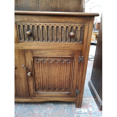 269 - A late 20th century oak linenfold Welsh dresser with upper two tier plate rack, two drawers and two ... 