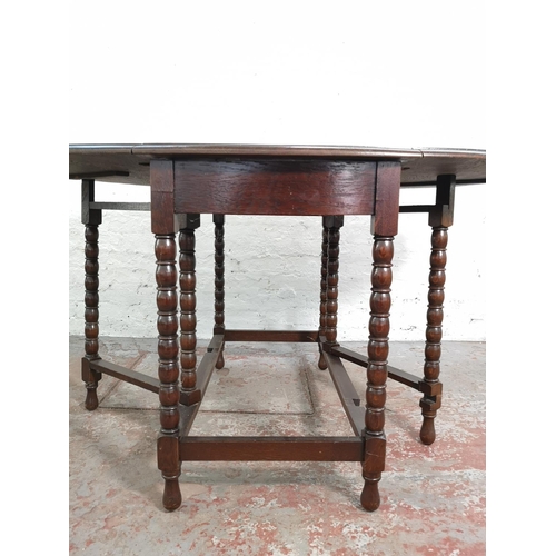 275 - An oak drop leaf gate leg oval dining table with bobbin turned supports - approx. 78.5cm high x 106c... 