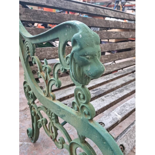 597 - A Victorian style cast iron and wooden slatted two seater garden bench with lions head design - appr... 