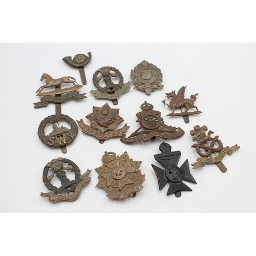 1083 - Twelve assorted vintage military cap badges to include Middlesex, North Staffs etc.