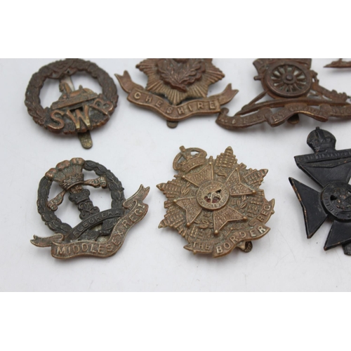 1083 - Twelve assorted vintage military cap badges to include Middlesex, North Staffs etc.