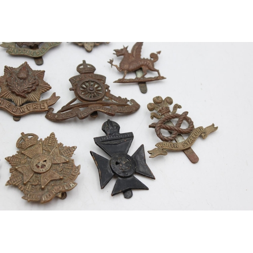 1083 - Twelve assorted vintage military cap badges to include Middlesex, North Staffs etc.