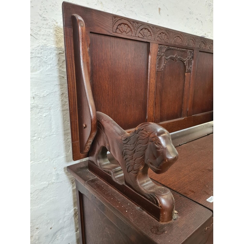 281 - An oak monk's bench with lion design armrests - approx. 98cm high x 95cm wide x 42cm deep