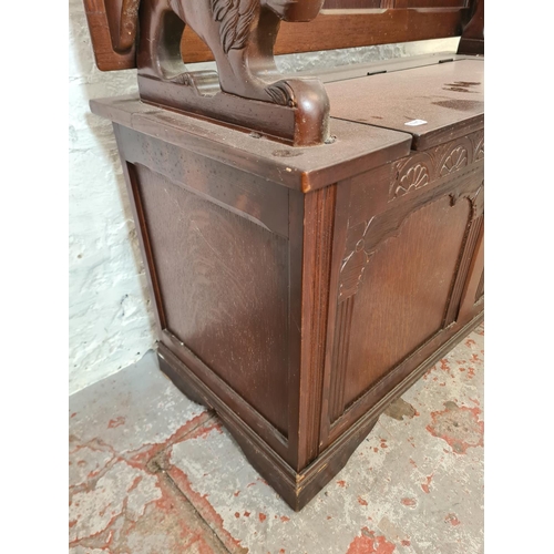 281 - An oak monk's bench with lion design armrests - approx. 98cm high x 95cm wide x 42cm deep