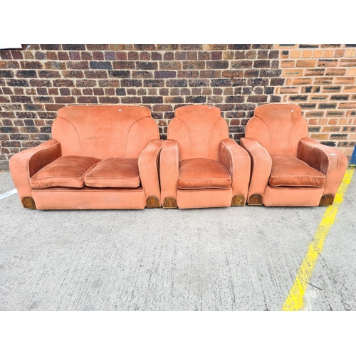 299 - An Art Deco salmon pink upholstered and carved oak three piece lounge suite comprising two armchairs... 