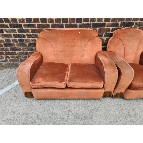 299 - An Art Deco salmon pink upholstered and carved oak three piece lounge suite comprising two armchairs... 