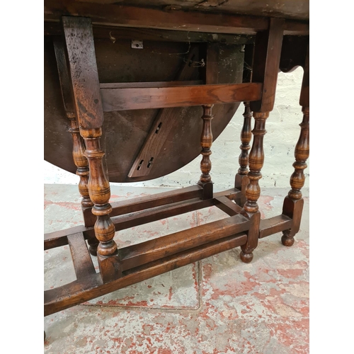 328 - An oak drop leaf gate leg oval dining table - approx. 73cm high x 108cm wide x 138cm long