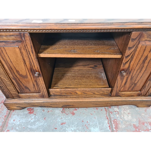 330 - An oak TV stand - approx. 63cm high x 105cm wide x 48cm deep