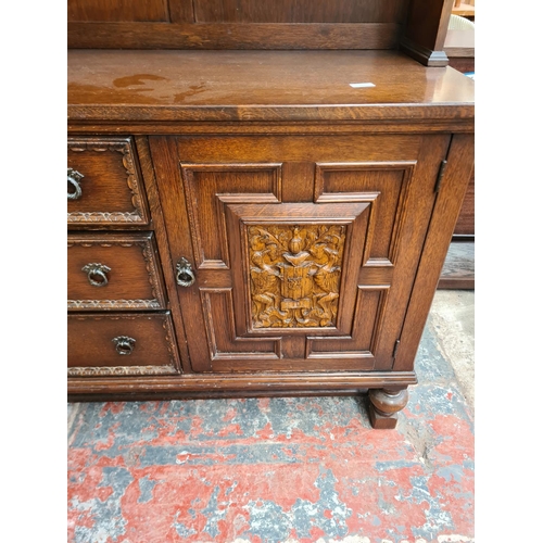 331 - A carved oak dresser with upper two tier plate rack, three drawers, two cupboard doors and baluster ... 