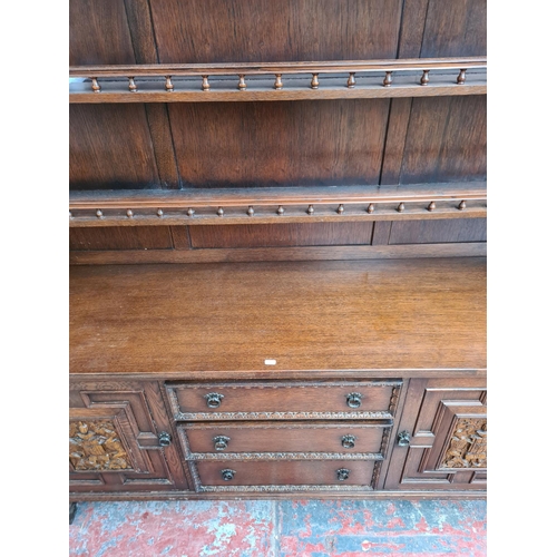 331 - A carved oak dresser with upper two tier plate rack, three drawers, two cupboard doors and baluster ... 