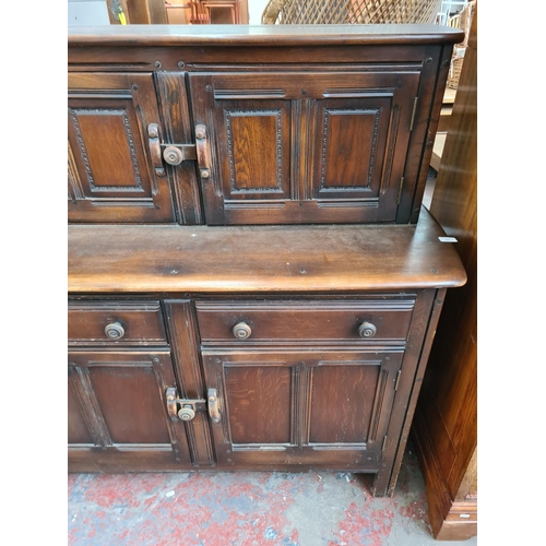 335 - An Ercol Old Colonial dark elm court cupboard with two upper doors, two drawers and two lower cupboa... 