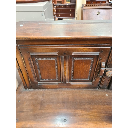 335 - An Ercol Old Colonial dark elm court cupboard with two upper doors, two drawers and two lower cupboa... 