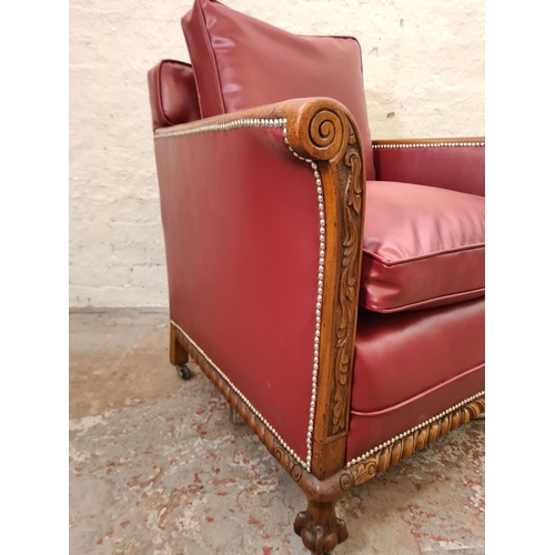 340 - A 1930s carved oak and red vinyl armchair with ball and claw supports and casters - approx. 96cm hig... 