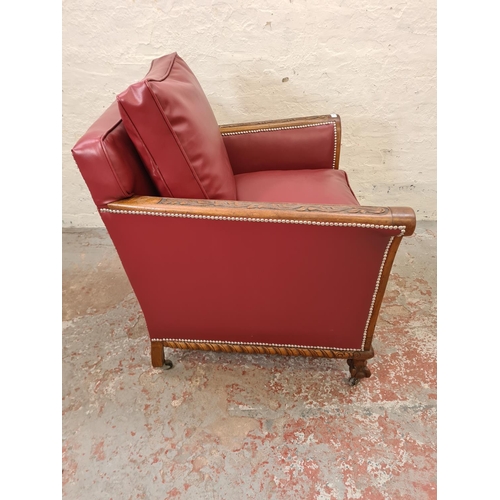 340 - A 1930s carved oak and red vinyl armchair with ball and claw supports and casters - approx. 96cm hig... 