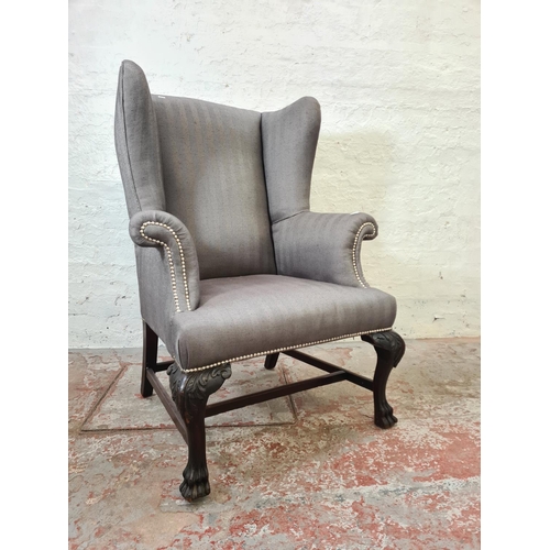 347 - An early 20th century grey upholstered wing back armchair with carved mahogany supports and lower st... 