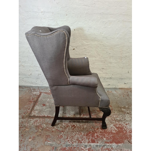 347 - An early 20th century grey upholstered wing back armchair with carved mahogany supports and lower st... 