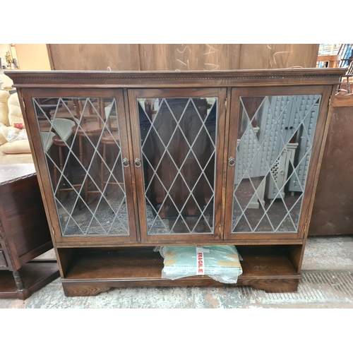 351 - An oak bookcase with three leaded glass doors and six internal glass shelves - approx. 138cm high x ... 