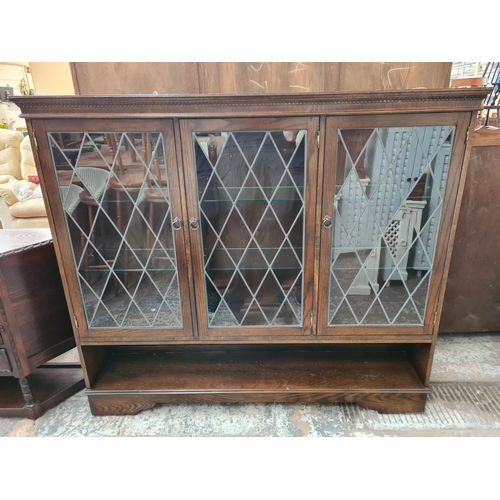 351 - An oak bookcase with three leaded glass doors and six internal glass shelves - approx. 138cm high x ... 