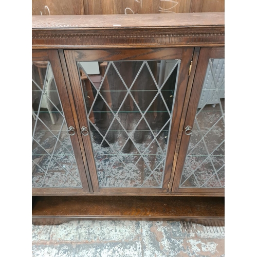 351 - An oak bookcase with three leaded glass doors and six internal glass shelves - approx. 138cm high x ... 