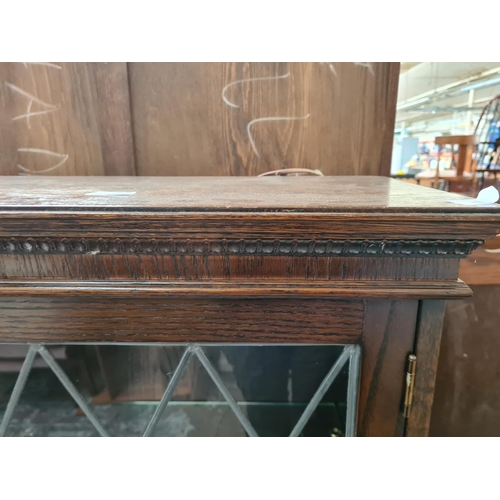 351 - An oak bookcase with three leaded glass doors and six internal glass shelves - approx. 138cm high x ... 